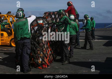 PHILIPPINISCHE SEE (7. April 2022) Matrosen entfernen während einer vertikalen Auffüllung auf See mit dem Militär-Sealift-Kommando Trockenfracht- und Munitionsschiff USNS Richard E. Byrd (T-AKE 4) die Ladungsnetze auf dem Flugdeck des Flugzeugträgers USS Abraham Lincoln (CVN 72). Die Abraham Lincoln Strike Group befindet sich im geplanten Einsatzgebiet der US-Flotte für 7., um die Interoperabilität durch Allianzen und Partnerschaften zu verbessern und gleichzeitig als reaktionsfähige Truppe zur Unterstützung einer freien und offenen Region im Indo-Pazifik-Raum zu dienen. (USA Navy Foto von Mass Communication Specialist Seaman Apprentice Ju Stockfoto