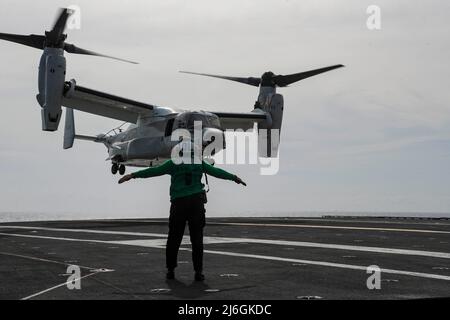 PHILIPPINE SEA (6. April 2022) Aviation Structural Mechanic (Safety Equipment) 2. Class Tyra Webb-Olam aus Detroit leitet einen CMV-22B Osprey, der den "Titanen" der Fleet Logistics Multi-Mission Squadron (VRM) 30 zugewiesen wurde, auf dem Flugdeck des Nimitz-Klasse-Flugzeugträgers USS Abraham Lincoln (CVN 72). Die Abraham Lincoln Strike Group befindet sich im geplanten Einsatzgebiet der US-Flotte für 7., um die Interoperabilität durch Allianzen und Partnerschaften zu verbessern und gleichzeitig als reaktionsfähige Truppe zur Unterstützung einer freien und offenen Region im Indo-Pazifik-Raum zu dienen. (USA Navy Foto von Mass Communication Stockfoto