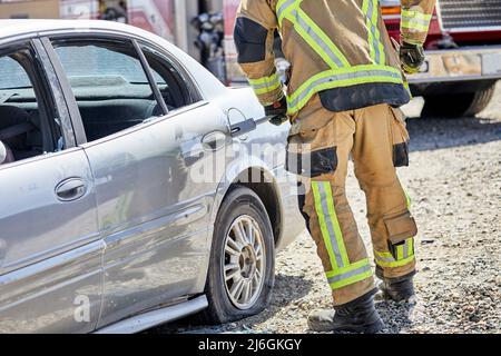 Feuerwehrmann, der während einer Demonstration eine Autotür aufhebt Stockfoto