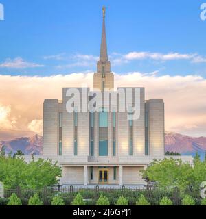 Quadratische Puffy Wolken bei Sonnenuntergang Fassade einer eingezäunten LDS Kirche gegen die Berge und Sonnenuntergang Himmel in Utah Stockfoto