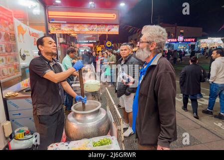 30. April, Lakemba, Sydney, Australien: In der letzten Nacht des Ramadan in Sydney ist das Ramadan Nights Festival von Sonnenuntergang um 17,30 Uhr bis zum 02,00. Am nächsten Morgen in vollem Gange. Hier unterhalten sich zwei Männer, während einer mit einem großen Holzpaddel einen großen Topf mit Dal-Essen, möglicherweise Dal Makhani, rührt. Stockfoto