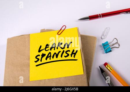 Spanisch Lernen. Lehrbücher und Schreibwaren auf weißem Hintergrund. Stockfoto