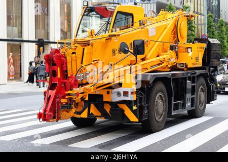 TOKIO, JAPAN - 28. April 2022: Ein Kran, der sich entlang einer Hauptstraße in Tokyos Ginza-Gegend bewegt. Im Hintergrund befindet sich ein Fendi-Laden. Stockfoto
