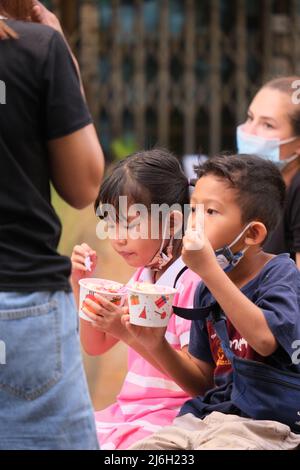 Phuket Thailand - November 21 2021: Kinder sind damit beschäftigt, auf einem Straßenmarkt buntes Eis zu essen Stockfoto