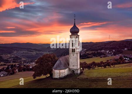 Seis am Schlern, Italien - Luftaufnahme der schönen St. Valentin Kirche (Kastelruth) bei Sonnenuntergang in den italienischen Dolomiten mit und bunten Wolken und Stockfoto