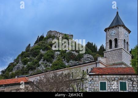Katholische Steinkirche mit mittelalterlicher Festung im Hintergrund Stockfoto
