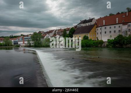 Schönes Panorama der Stadt Steyr in Oberösterreich, die sich über dem Fluss Enns am grünen Flussufer erhebt. Fluss und kleine Stromschnellen im Vordergrund Stockfoto