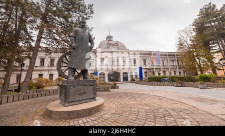 Weißes Gebäude in Kragujevac, großes Kolosseum-Gebäude in der serbischen Stadt, das an einem bewölkten Tag einst das Hauptquartier eines großen Automobilherstellers war. Stockfoto