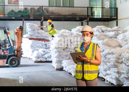 Ein Lagerhaus für Frauen trägt eine Maske, die im Lager für Alaun oder Chemikalien arbeitet. Internationales Exportgeschäftskonzept. Stockfoto