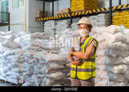 Eine weibliche Lagerarbeiterin trägt eine Maske im Lager für Alaun oder Chemikalien. Internationales Exportgeschäftskonzept. Stockfoto