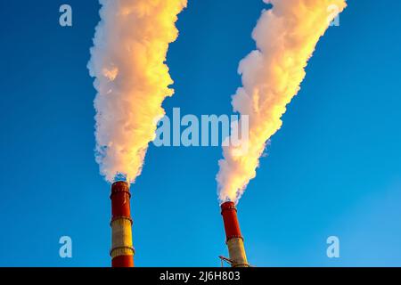 Weißer Rauch kommt aus den Rohren am blauen Himmel Stockfoto