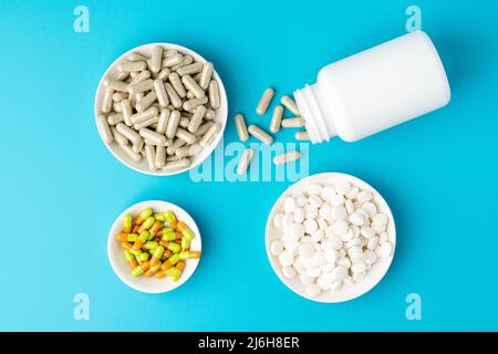 Blauer Hintergrund einer großen Gruppe von verschiedenen Kapseln, Pillen und Tabletten in Flasche und Schüssel Stockfoto