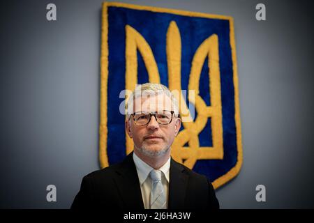 27. April 2022, Berlin: Andrij Melnyk, Botschafter der Ukraine in Deutschland, blickt vor dem Wappen der Ukraine im Botschaftsgebäude am Rande eines Gesprächs mit Journalisten der Deutschen Presseagentur in die Kamera des Fotografen. Foto: Kay Nietfeld/dpa Stockfoto