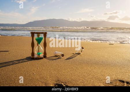 Nahaufnahme der Sanduhr auf dem Sand.Timer Strand Sonnenuntergang Stockfoto