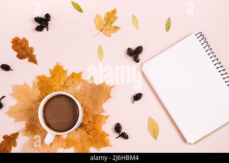 Flache Lay-Komposition mit trockenen Ahornblättern, Notizbuch und Kaffee-Latte-Tasse auf rosa Hintergrundwand im Studio. Kreativer Herbst, Dank, Herbst Stockfoto