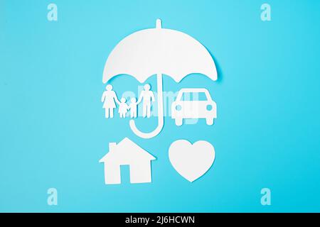 Regenschirm Abdeckung Familie, Haus und Auto Form Papier auf blauem Hintergrund. Internationaler Familientag, Gesundheits-, Wellness- und Versicherungskonzept Stockfoto