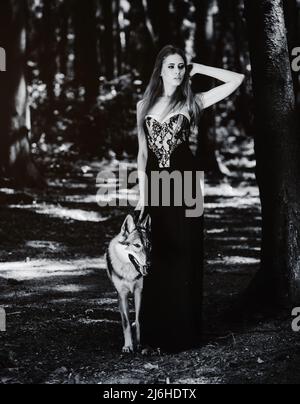 Porträt einer Frau in einem schwarzen Kleid mit Ein Hund im Wald Stockfoto