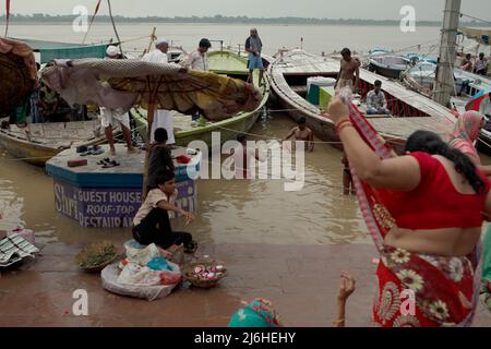 Die Pilger nehmen ein Badritual ein, da die anderen am Ufer des Flusses oder auf den geparkten Booten stehen, wenn Ganges überschwemmt wird, in Dasasaswamedh Ghat in Varanasi, Uttar Pradesh, Indien. Stockfoto