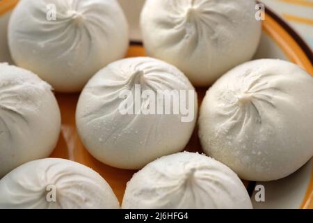 Tiefgefrorenes khinkali auf einem Teller aus der Nähe. Rohe Khinkali, gefüllt mit Fleisch. Teig und Fleischprodukte. Gefrorene Halbzeuge. Stockfoto