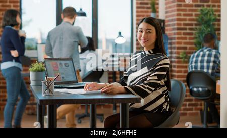 Porträt eines asiatischen HR-Mitarbeiters, der CV-Informationen von Kandidaten analysiert, bevor er an einem Vorstellungsgespräch teilnimmt und über die Beschäftigung spricht. Frau, die sich Lebenslaufakten ansieht und im Büro des Unternehmens lächelt. Stockfoto