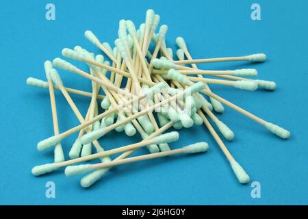 Ohrstöpsel aus Baumwolle, Holzstäbchen. Ohrreiniger – Haufen grüner Wattestäbchen. Set mit Ohrstöcken aus Baumwolle auf blauem Hintergrund Stockfoto