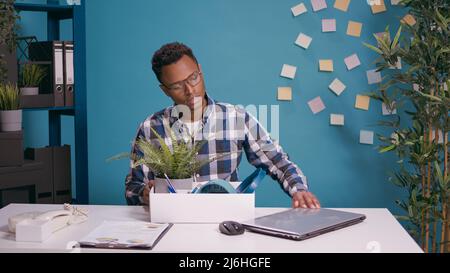 Frustrierte Person, die nach dem Abschuss aus dem Büro Sachen in einen Karton packte. Unglücklicher Mann, der sich Sorgen über Arbeitslosigkeit macht und Dinge sammelt, nachdem er entlassen und entlassen wurde. Stockfoto