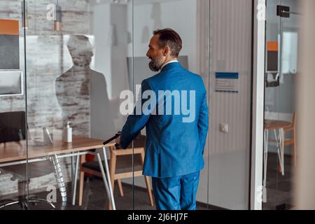 Serious kaukasischen Geschäftsmann beim Betreten der Tür im Büro Stockfoto