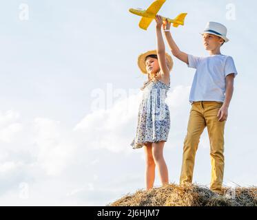 Portrait von Kindern Junge und Mädchen spielen im Freien. Leichter, sonniger Tag. Fröhliches und ruhiges Konzept. Frische Luft auf dem Land. Kinder tragen Hüte und Stockfoto
