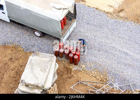 Brennbares Gas in roten Flaschen wird in einen Kippwagen geladen, um sie selektiv bis zum Punkt oder zur Wartung des Befüllens oder Austauschs von Flaschen zu liefern Stockfoto