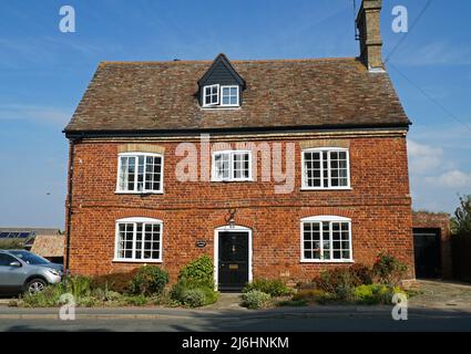 Wunderschönes altes rotes Backsteinhaus mit Doppelfassade in Dorflage. Stockfoto