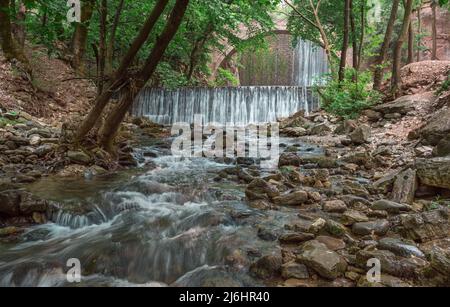 Die alte, gewölbte Steinbrücke zwischen zwei Wasserfällen in Palaiokaria, Präfektur Trikala, Thessalien, Griechenland. Stockfoto