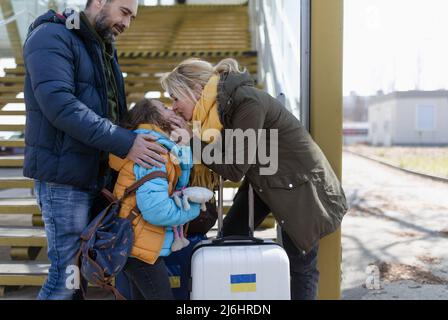 Ukrainische Flüchtlingsfamilie mit Gepäck am Bahnhof zusammen, ukrainisches Kriegskonzept. Stockfoto