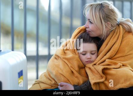 Deprimierte ukrainische Einwanderer sitzen und warten am Bahnhof. Stockfoto