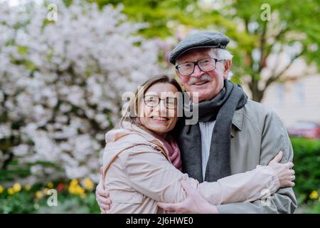 Erwachsene Tochter umarmte ihren älteren Vater im Park am Frühlingstag. Stockfoto