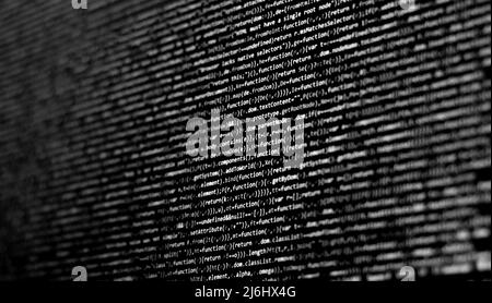Selektiver Fokus weiße graue Codes auf dem schwarzen Bildschirm. Verschwommene Codierung Seitenansicht. Remote-Arbeit. Software-Entwickler. Stockfoto