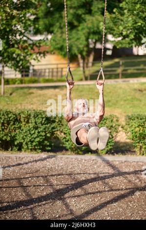 Ein reifer grauhaariger Mann, der im Park trainiert Stockfoto