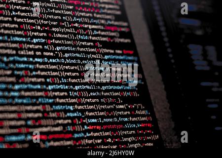 Code schreiben auf dem Büro-Computer-Bildschirm. Rote Buchstaben intensiv. Web-Quellen kreative Lösungen für die digitale Welt. Seitenansicht des Monitors. Stockfoto
