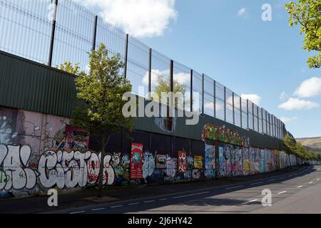 Die „Friedenslinie“, die die Grenze zwischen dem Gebiet der Catholic Falls Road (hinter der Mauer) und dem Gebiet der Protestant Shankill Road, Cupar Way, WestBelfast, N, trennt Stockfoto
