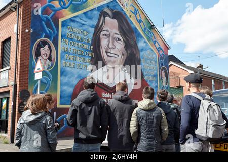 Reisegruppe aus Spanien am Bobby Sands Wandgemälde an der Wand des Sinn Fein Büros, Lower Falls Road, West Belfast, Nordirland, 20.. April Stockfoto