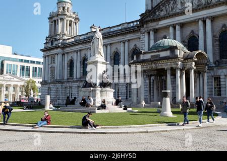 Die Menschen genießen die Frühlingssonne auf dem Gelände des Belfast City Hall, Nordirland, 20.. April 2022. Stockfoto