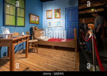 London Shoreditch, Großbritannien. 30. April 2022. Familie mit Kindern vor der Nachbildung von Bedroom in Arles bei Van Gogh die Immersive Experience Ausstellung Stockfoto