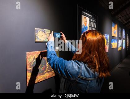 London, Großbritannien. 30. April 2022. Frau, die mit ihrem Telefon Fotos von Exponaten in der Ausstellung „The Immersive Experience“ von Van Gogh mit Werken von Künstlern fotografiert. Stockfoto