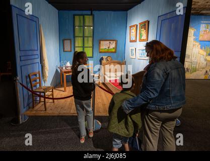 London Shoreditch, Großbritannien. 30. April 2022. Familie mit Kindern vor der Nachbildung von Bedroom in Arles in der Vincent van Gogh Immersive Experience Ausstellung Stockfoto