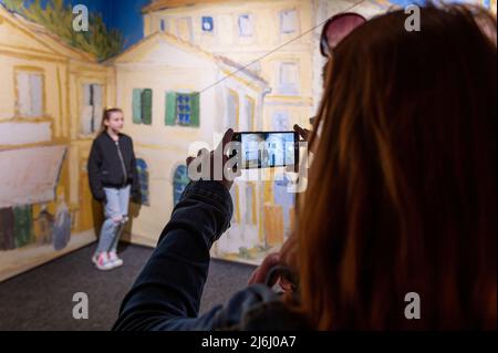 London Shoreditch, Großbritannien. 30 April 2022. Die Familie fotografiert mit dem Mobiltelefon im Hintergrund der Stadt Arles bei Van Gogh die Ausstellung „Immersive Experience“ Stockfoto