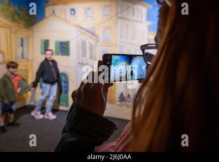 London Shoreditch, Großbritannien. 30 April 2022. Die Familie fotografiert mit dem Mobiltelefon im Hintergrund der Stadt Arles bei Van Gogh die Ausstellung „Immersive Experience“ Stockfoto