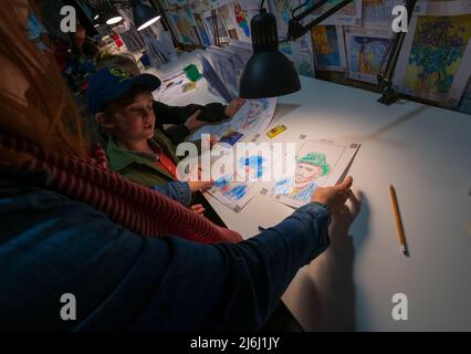 London Shoreditch, Großbritannien. 30. April 2022. Eltern mit Kindern malen einen Druck bei Van Gogh die Immersive Experience Ausstellung. Stockfoto