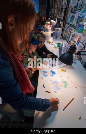 London Shoreditch, Großbritannien. 30. April 2022. Eltern mit Kindern malen einen Druck bei Van Gogh die Immersive Experience Ausstellung. Stockfoto