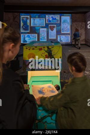 London, Großbritannien. 30. April 2022. Eltern mit Kindern malen und scannen Bilder für die Bildschirmanzeige bei Van Gogh die Immersive Experience Ausstellung. Stockfoto
