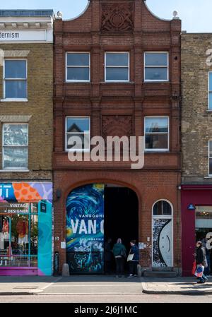 London Shoreditch, Großbritannien. 30. April 2022. Blick auf die Straße vor dem Eingangstor mit Personen, die Van Gogh die Ausstellung „Immersive Experience“ betreten. Stockfoto