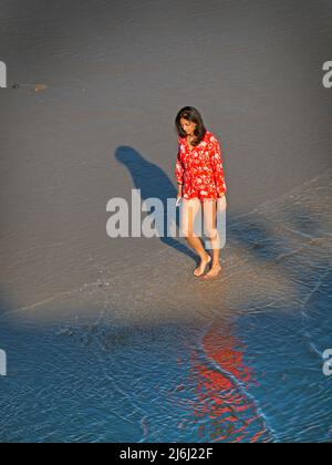 Eine Dame spaziert am Sandstrand von Brighton entlang Stockfoto
